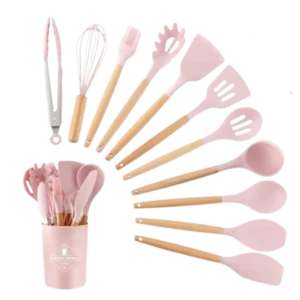Set de cocina de 12 piezas en color rosa con mangos de madera, incluye utensilios como espátulas, cucharas, batidor y pinzas, organizados junto a un recipiente para almacenamiento